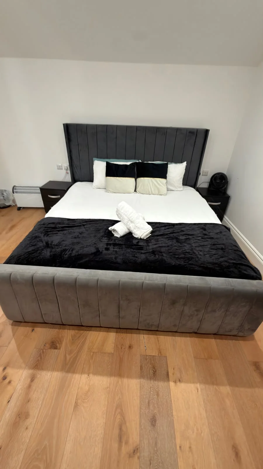 Prepared bedroom with black bed runner and folded white towels
